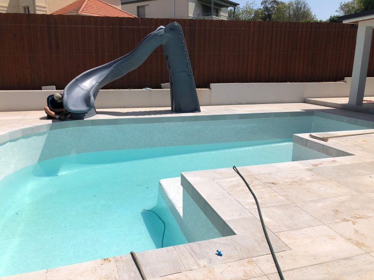 Professional installation of a genuine SR Smith pool slide at a residential swimming pool in Sydney.